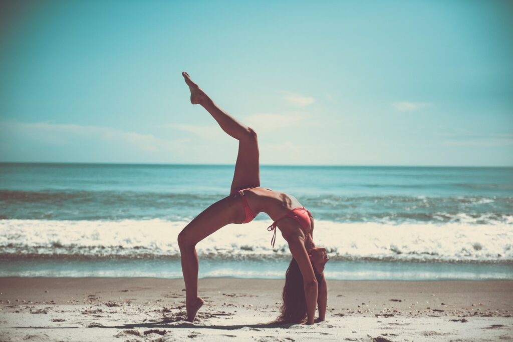 Mulher praticando yoga na praia, promovendo autoestima e bem-estar.