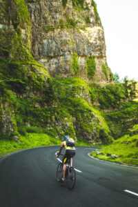 Ciclista em ação descendo uma pista entre montanhas cobertas de vegetação exuberante.