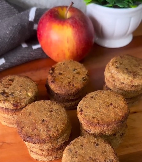 Imagem de uma maçã e vários Biscoitos Fit de Maçã e Canela sobre uma mesa, uma opção deliciosa e saudável para quem busca equilíbrio.