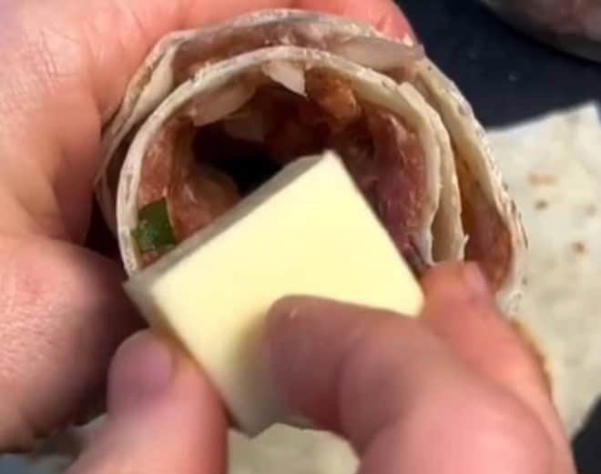 Imagem do queijo sendo adicionado no centro da tortilha com carne moída.