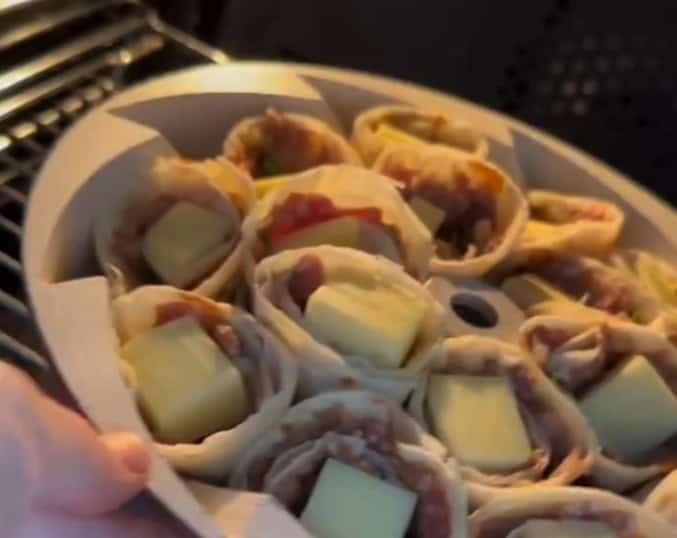 Imagem das tortilhas com carne moída e queijo sendo levadas ao forno para serem assadas.