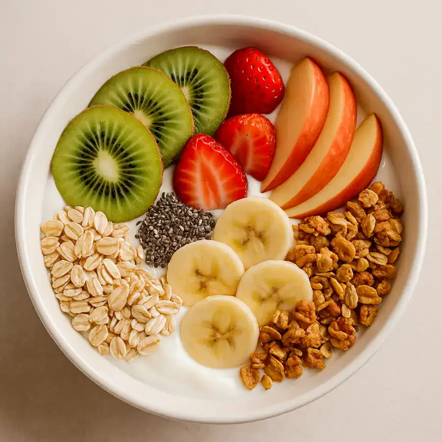 Tigela colorida com frutas, iogurte, granola e sementes, representando alimentos ricos em fibras na dieta.