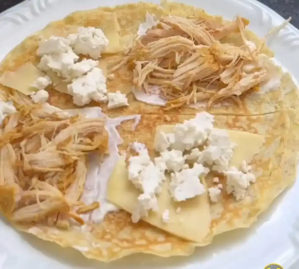Recheio de frango e queijo sendo distribuído nas partes do crepe saudável