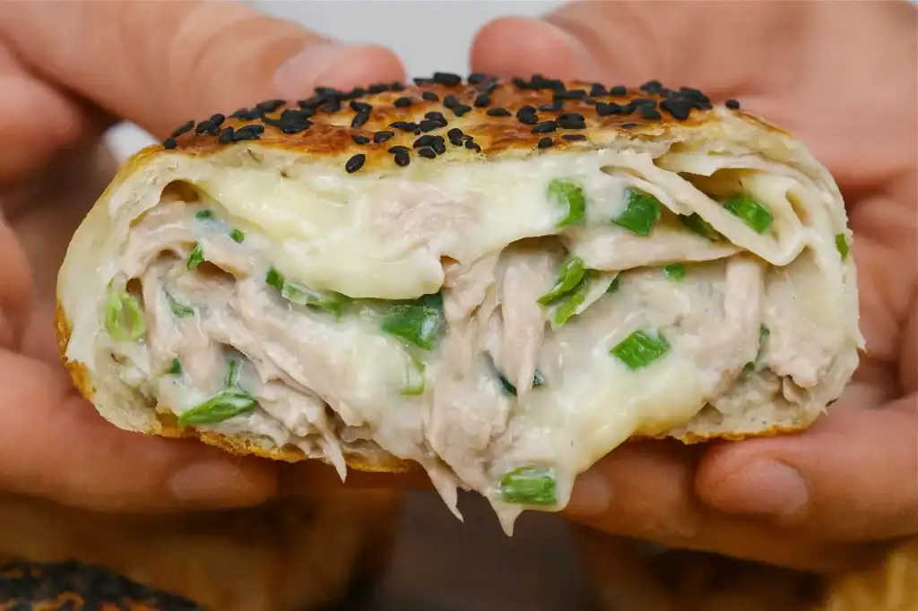 Close do interior cremoso do Hot Pocket de Atum, mostrando queijo derretido e cebolinha.
