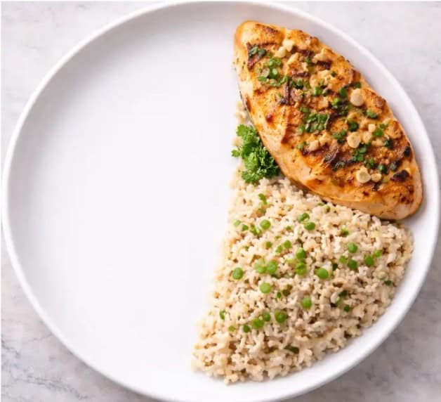 Metade de um prato saudável com salmão grelhado e arroz integral representando proteína e carboidrato complexo